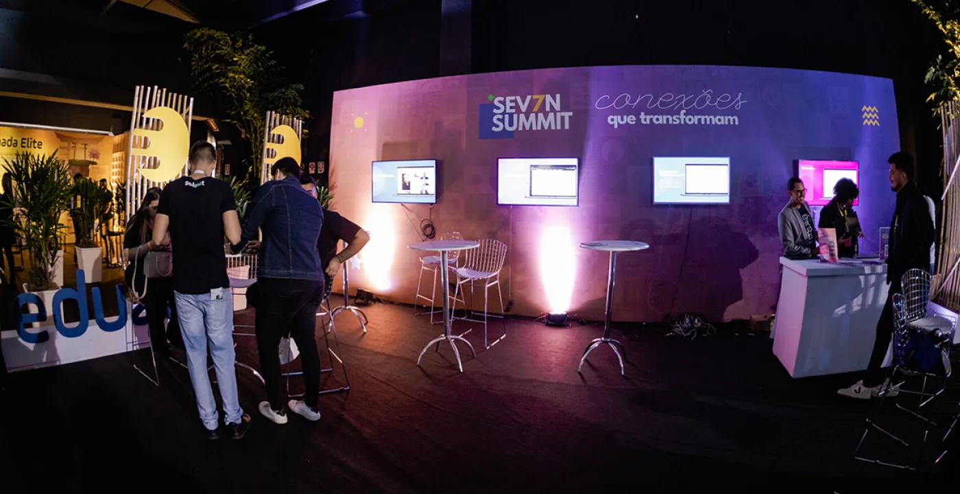 Área de convivência com telas e sinalização do evento